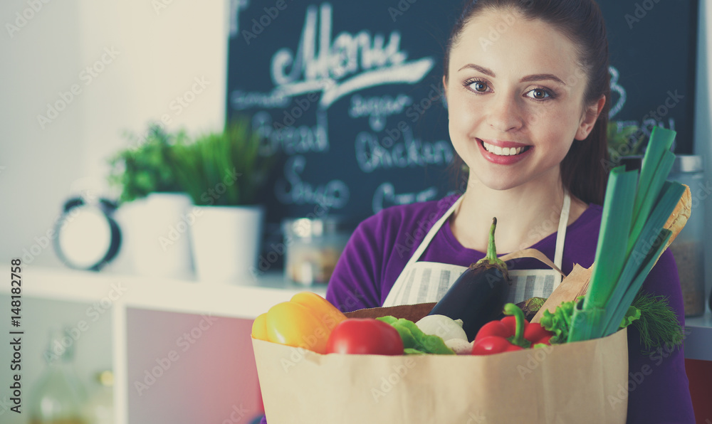 Young woman holding grocery shopping bag with vegetables Standing in the kitchen Young woman holding grocery shopping bag with vegetables Standing in the kitchen