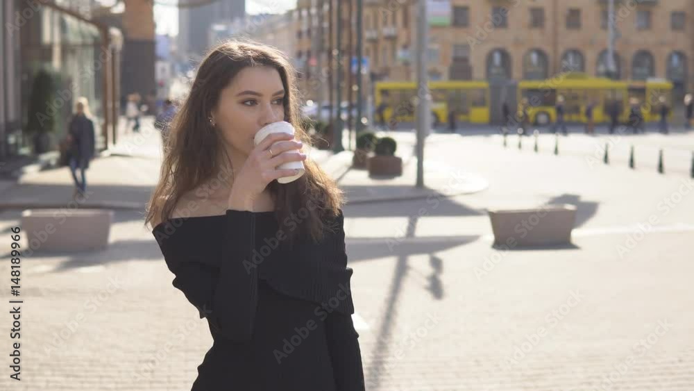 Business woman walking outdoors holding a cup of coffee Business woman walking outdoors holding a cup of coffee