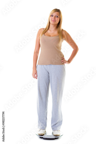 Happy woman wearing tracksuit standing on weighing machine