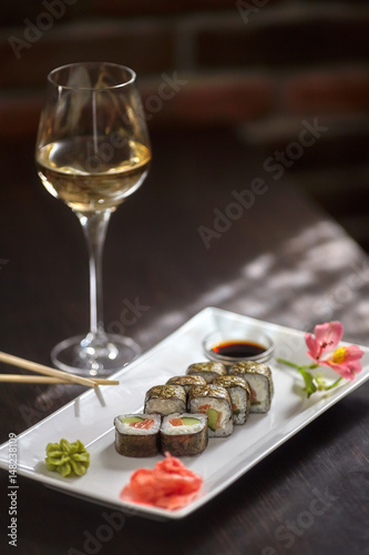 Sushi rolls on white plate and glass of wine