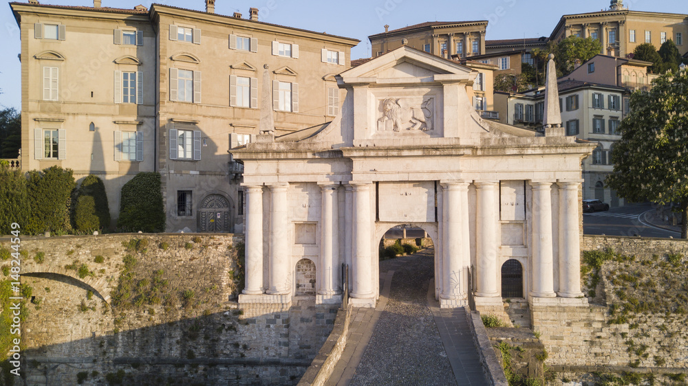 Obraz premium Bergamo - Old city. One of the beautiful city in Italy. Aerial shot of the old gate named Porta San Giacomo during the sunrise and a wonderful blu day