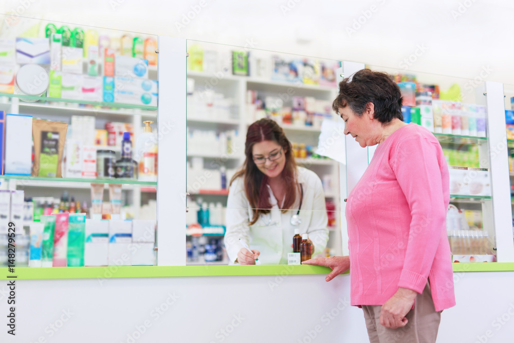 Female pharmacist discusses prescription medication with senior customer at pharmacy Female pharmacist discusses prescription medication with senior customer at pharmacy