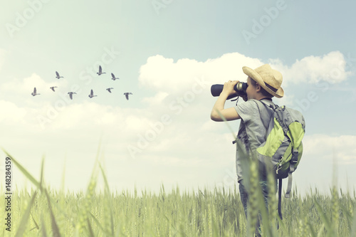 Young birdwatcher looks with his binoculars the bird world