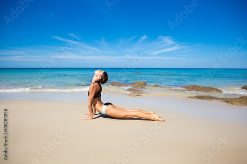 Healthy yoga exercise on the beach  slim sporty body training  leisure and meditation  vacation  sport  health care concept  over natural background blue sky and sea. Cobra pose