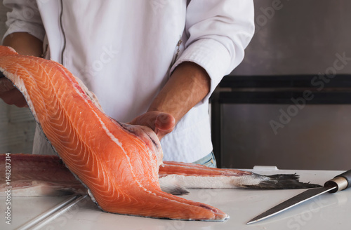 Fotografia Chef's hand holding fresh piece of salmon