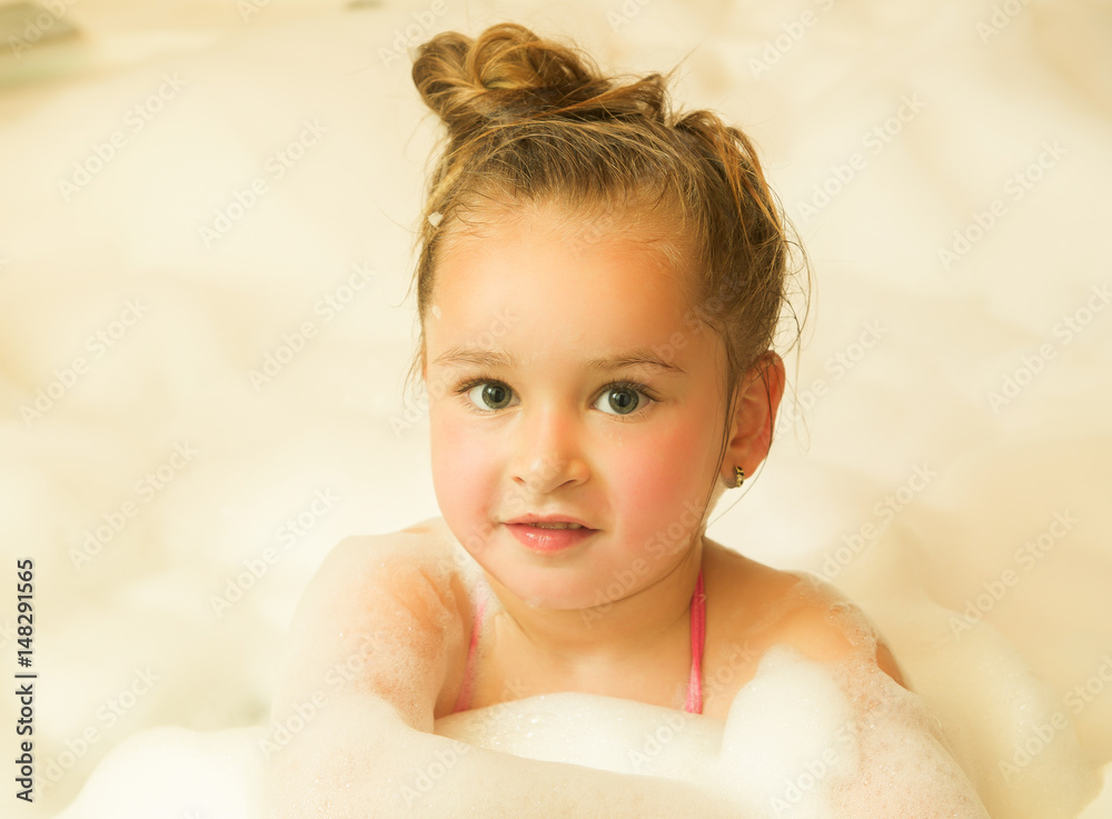 little beautiful girl posing inside of a bathtub with water and foam in bath little beautiful girl posing inside of a bathtub with water and foam in bath