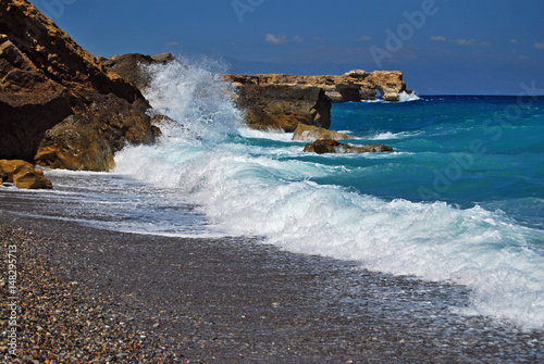 Stormy sea with wave and rock in sunny day.