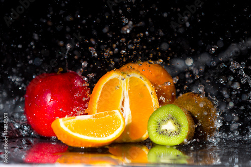 Fototapeta Naklejka Na Ścianę i Meble -  Multivitamin in water spalsh and drops on black background. Fresh fruits in water spray, multi fruits.