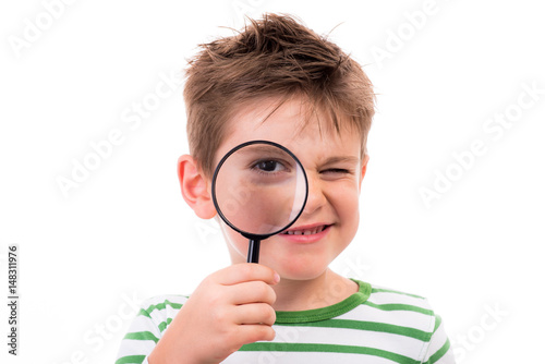 kind hält eine lupe ans auge