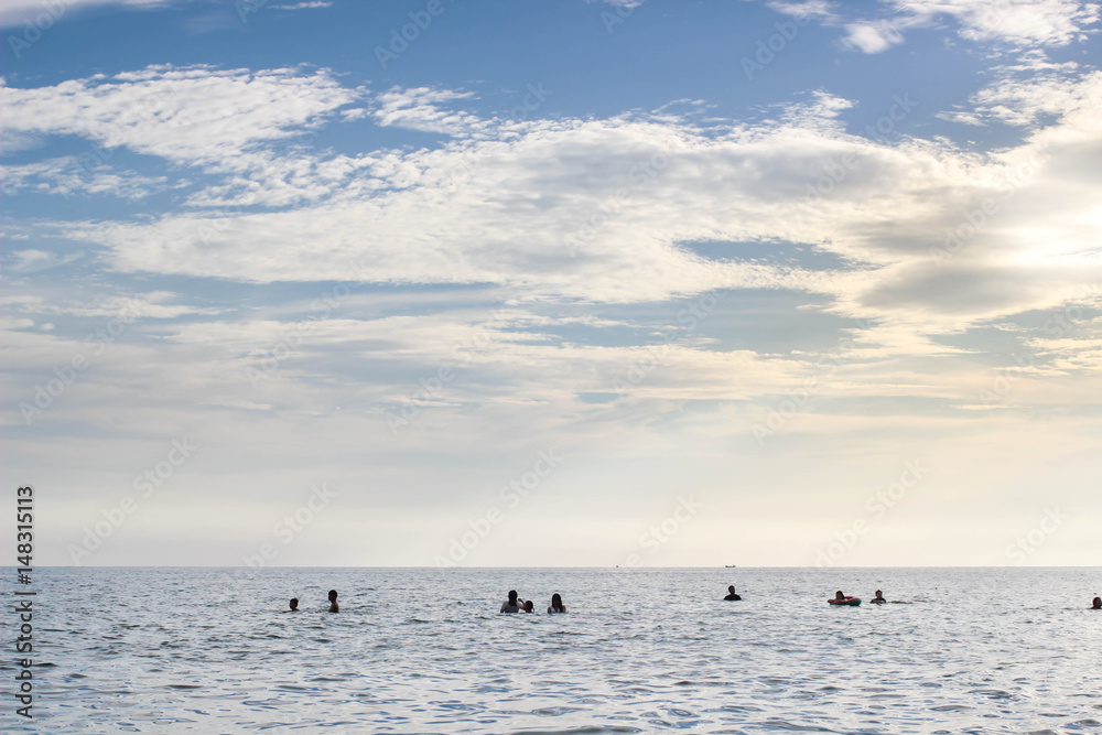Fototapeta premium People in the sea with blue sky and sunlight in the evening.