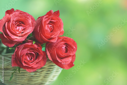 beautiful red roses flower basket over green background in vintage tone with copy space