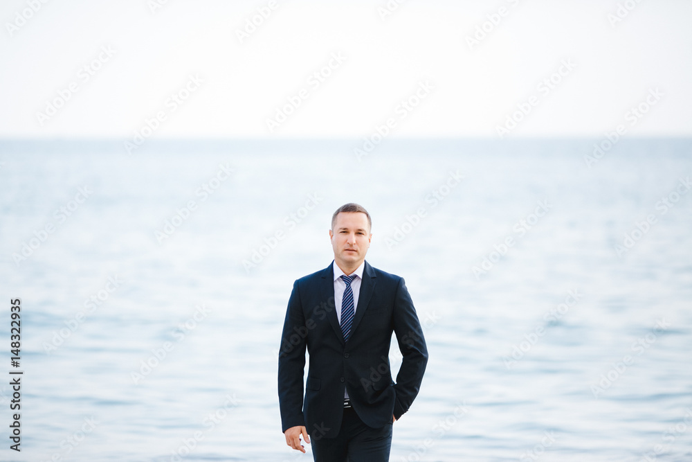 The handsome groom stands near sea The handsome groom stands near sea