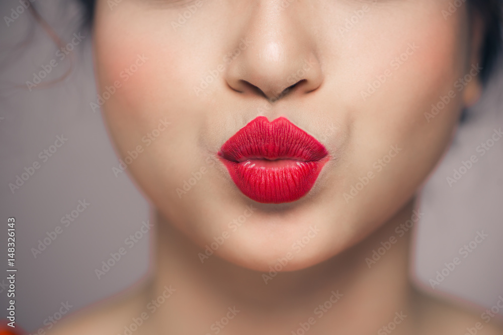 Woman's lips blowing a kiss with bright red lipstick Woman's lips blowing a kiss with bright red lipstick