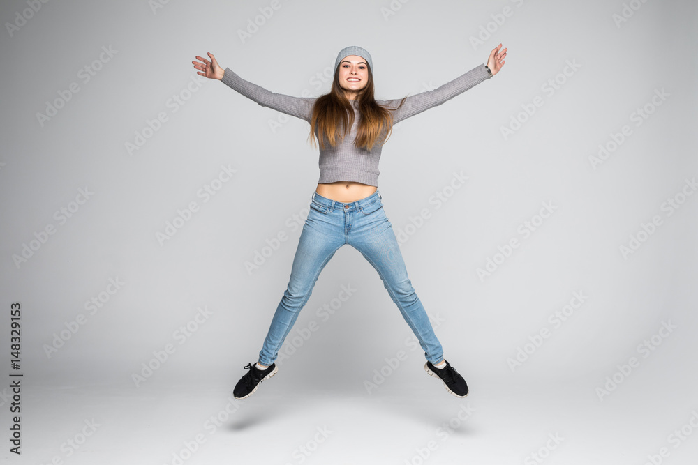 Obraz premium Urocza szczęśliwa kobieta skacze z radości na szarym tle