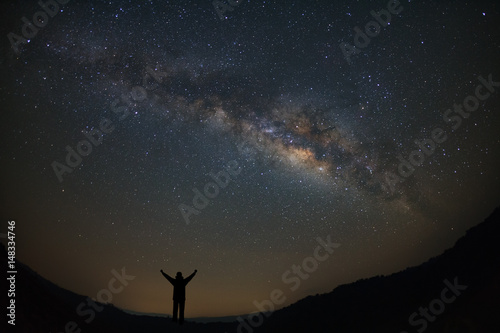 Landscape milky way galaxy with stars and silhouette of a standing happy man, Long exposure photograph, with grain.