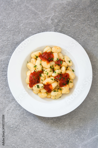Gnocchi with tomato sauce on gray stone.Top view
