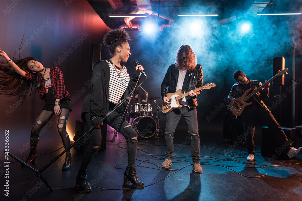 Fototapeta premium Young multiethnic rock and roll band performing hard rock music on stage