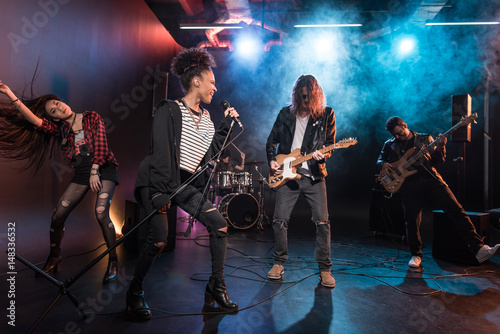 Young multiethnic rock and roll band performing hard rock music on stage