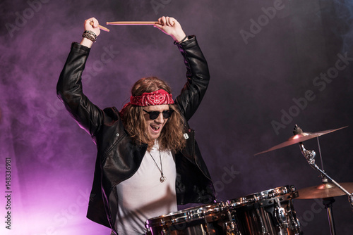 Handsome young man playing hard rock music with drums set