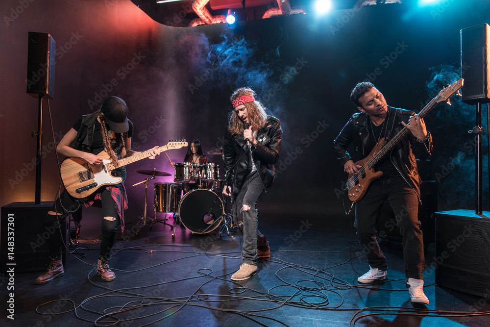 Fototapeta premium Handsome singer with rock and roll band performing music on stage