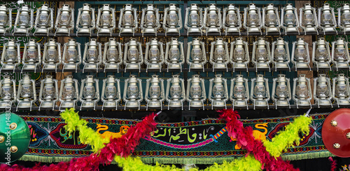 Foto TEHRAN, IRAN - October 12, 2016: kerosene lamps and the name Fatima embroidered on fabric in front of a mosque, as a symbol of religious mourning of Imam Husayn martyrdom in the Battle of Karbala