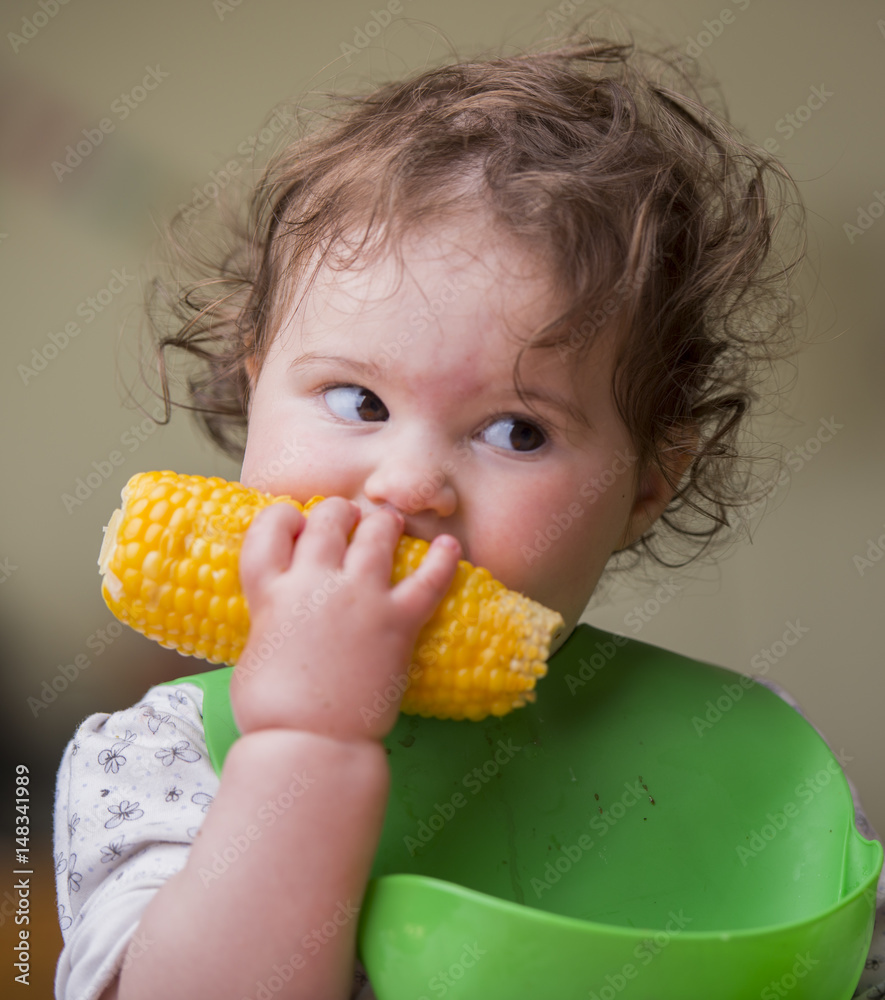 cute baby girl eating corn, looking aside cute baby girl eating corn, looking aside