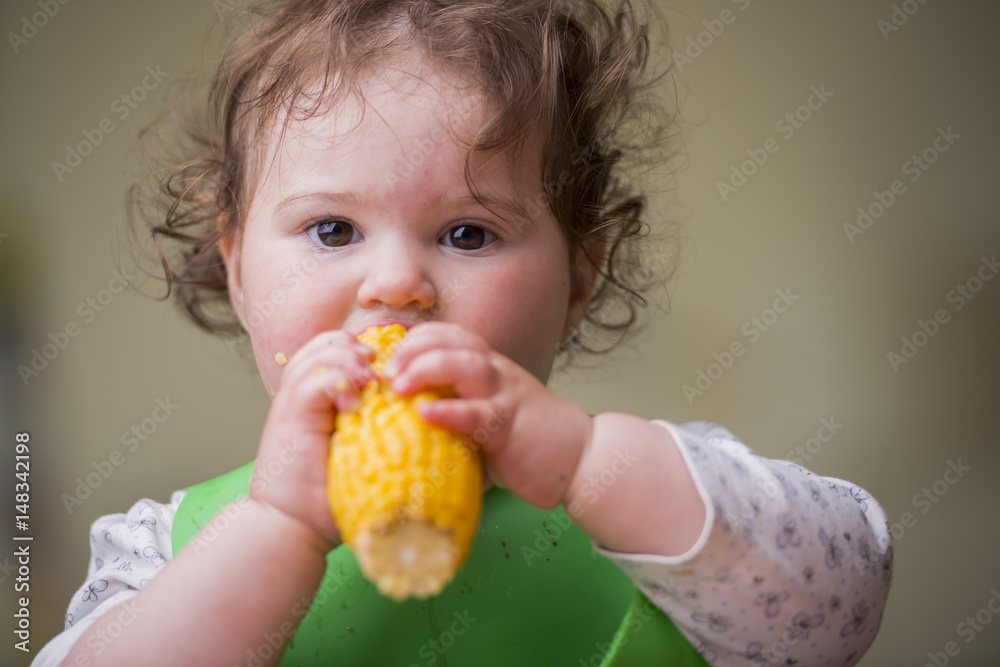 cute baby girl eating corn, looking straight cute baby girl eating corn, looking straight