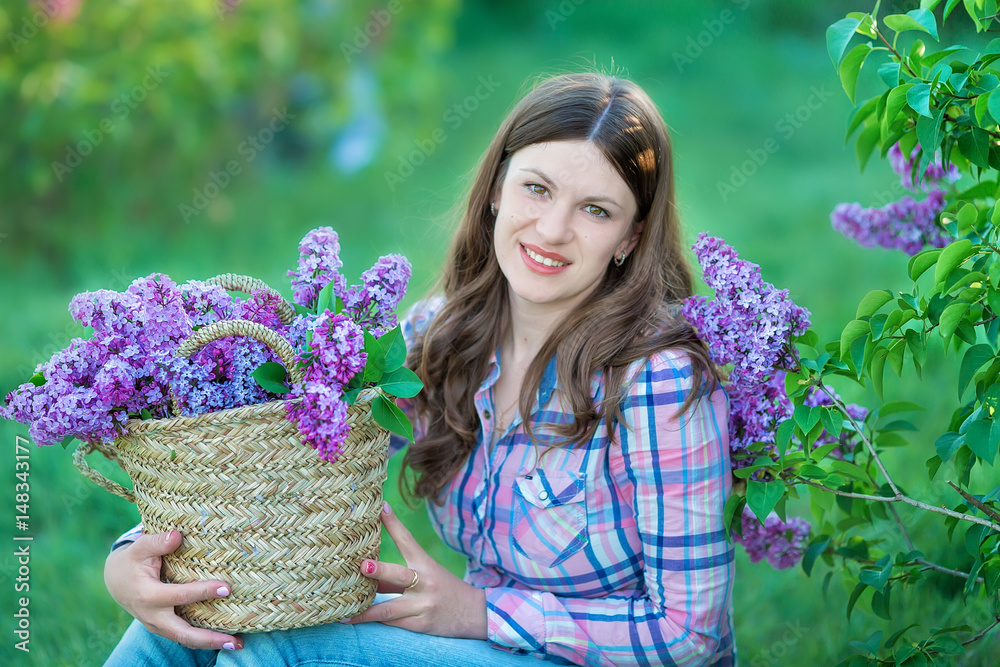 Beautiful woman enjoying lilac garden, young woman with flowers in green park. girl tearing the lilac in the garden Beautiful woman enjoying lilac garden, young woman with flowers in green park. girl tearing the lilac in the garden