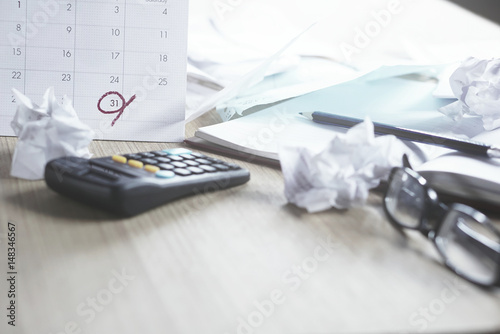 messy office desk during tax season with deadline on a calendar,calculator, unfinished document, and late payment, office life concept