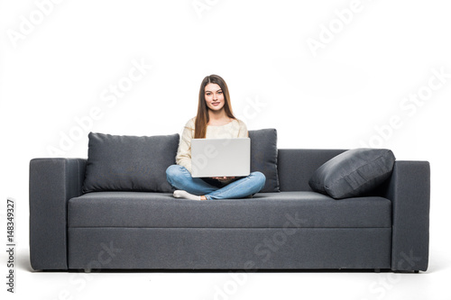 Young woman lying on couch and using laptop at home