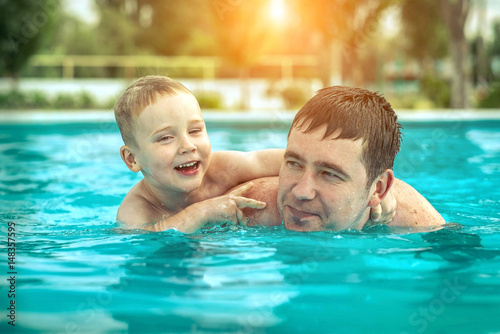 Father and son funny in  water pool under sun light at summer da