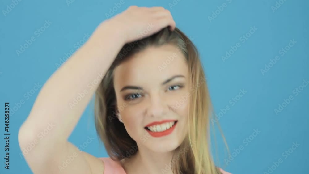 Closeup Portrait of Beautiful Woman with Long Dark Hair, Pink Dress and Charming Smile Posing in Studio on Blue Background. Closeup Portrait of Beautiful Woman with Long Dark Hair, Pink Dress and Charming Smile Posing in Studio on Blue Background.