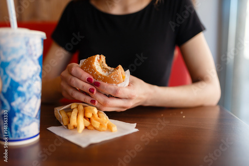 Obraz na plátně Young girl holding in female hands fast food burger, american unhealthy meal on