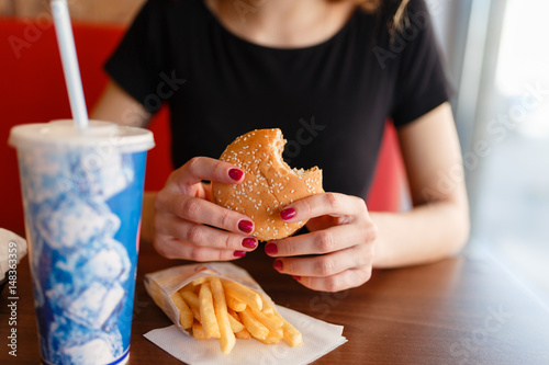 Wallpaper Mural Young girl holding in female hands fast food burger, american unhealthy meal on blue background, mockup with copy space for text message or design, hungry human with grilled hamburger front view Torontodigital.ca
