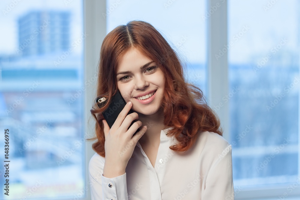 Fototapeta premium slender woman in a light shirt, smile, red hair, work