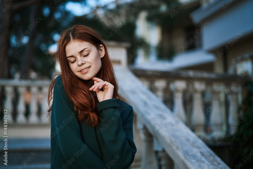 Fototapeta premium an elegant lady in a green sweater descends the steps holding onto the railing