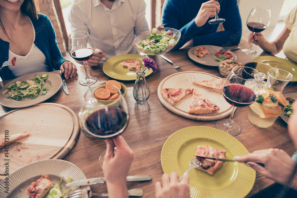 Close up of nicely served wooden table with tasty dishes and glasses of wine. People are having fun at the party Close up of nicely served wooden table with tasty dishes and glasses of wine. People are having fun at the party
