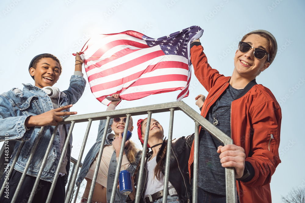 Fototapeta premium teenagers having fun and waving american flag in skateboard park, hipster style concept