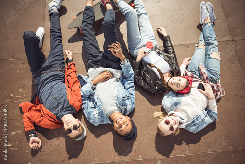 High angle view of teenagers group lying together and resting at skateboard park