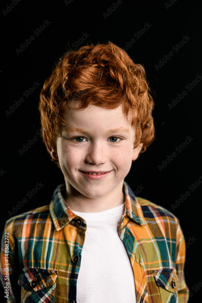 portrait of adorable redhead boy smiling and looking at camera isolated on black portrait of adorable redhead boy smiling and looking at camera isolated on black