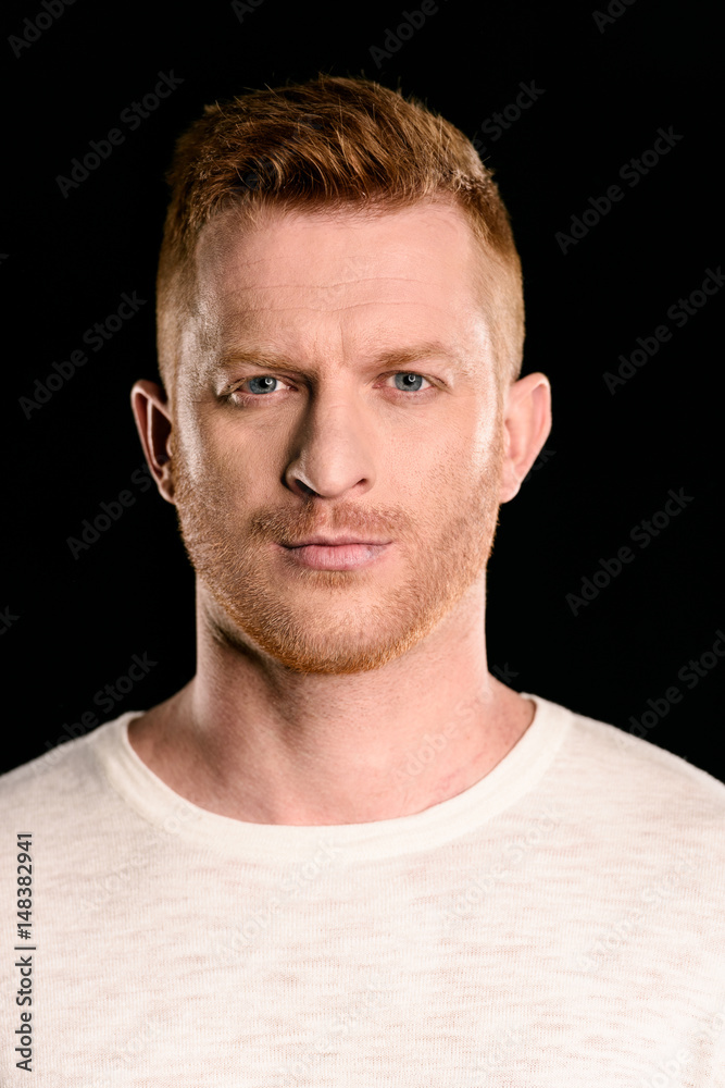 Obraz premium portrait of handsome redhead man posing and looking at camera isolated on black