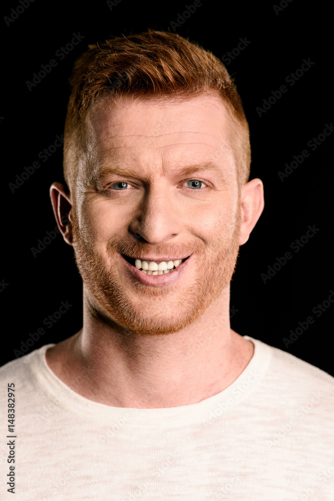 Fototapeta premium portrait of handsome redhead man smiling isolated on black