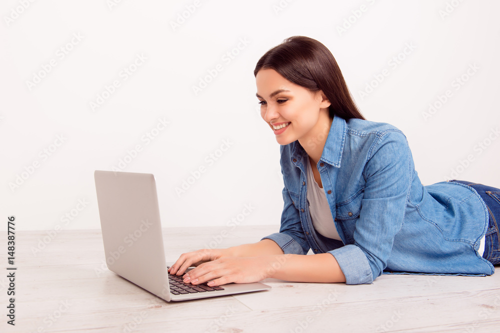 Happy smiling girl lying on the floor and typing letter on her laptop Happy smiling girl lying on the floor and typing letter on her laptop