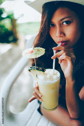 Young beautiful woman drinking cocktail with pineapple in beach