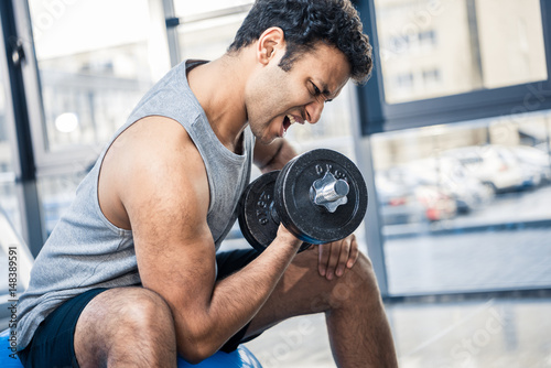 Handsome young man workout with dumbbell at gym