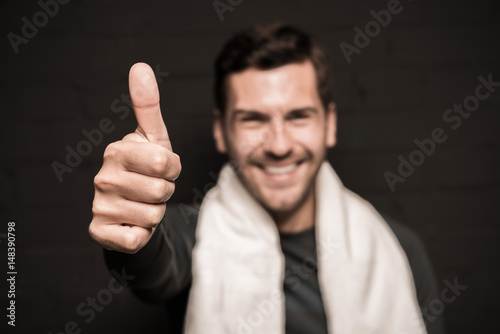 Close-up portrait of handsome man with towel on shoulders, showing thumb up