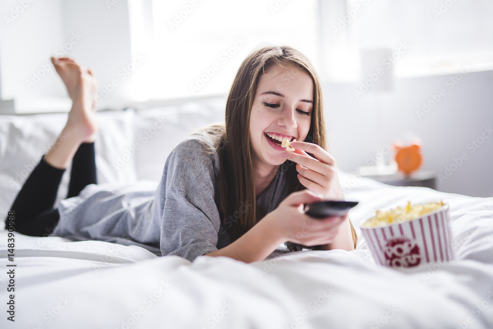 young teenager watching movies in bed with popcorn