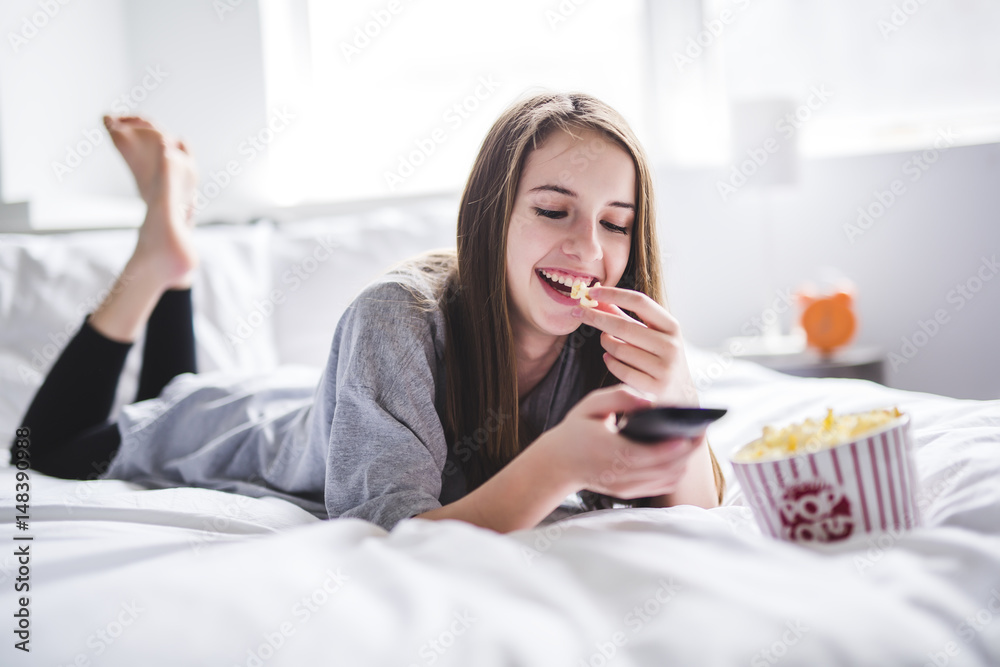 young teenager watching movies in bed with popcorn young teenager watching movies in bed with popcorn