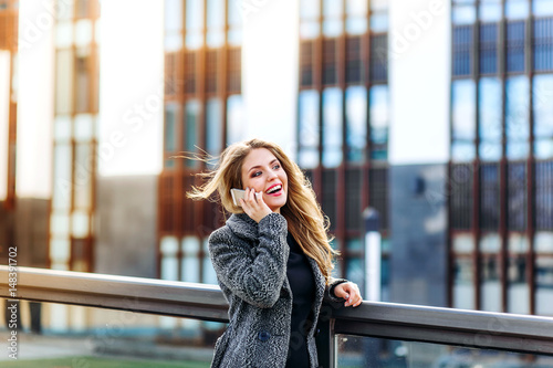 Pleasant modern attractive young woman holding mobile phone, talking with friend and relaxing in the cafe on buiding nature background. Free Download Pleasant modern attractive young woman holding mobile phone, talking with friend and relaxing in the cafe on buiding nature background. - GFXLoad