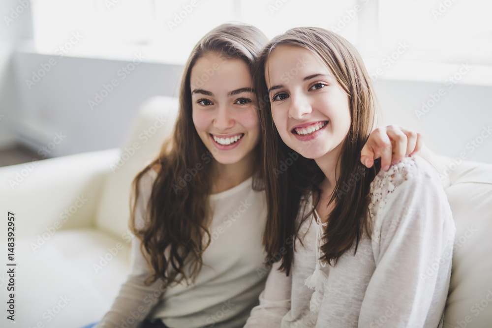 closeup portrait of hugging 2 beautiful young women having fun on sofa closeup portrait of hugging 2 beautiful young women having fun on sofa